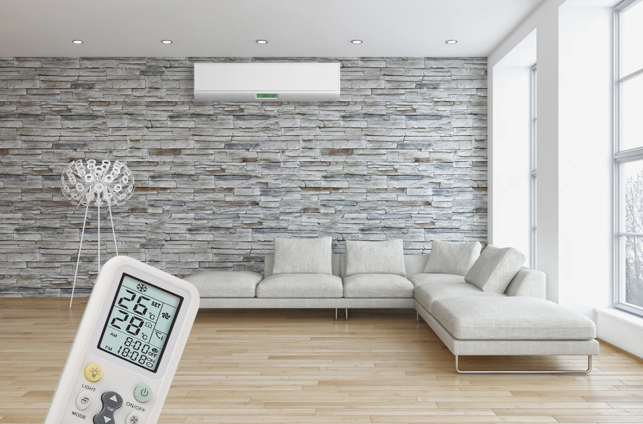 Salon moderne avec climatiseur mural blanc installé sur mur en pierres naturelles grises