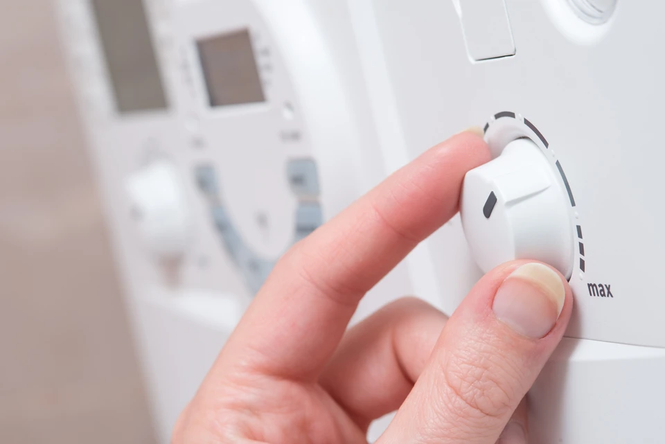Intérieur domestique moderne avec main ajustant un thermostat mural blanc